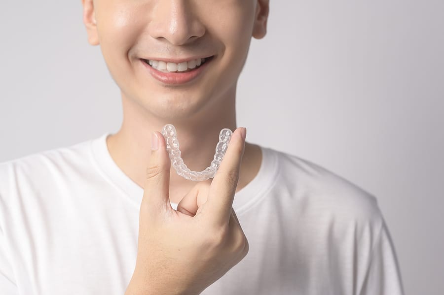 Can Invisalign Fix Deep Bite? 2 Man Holding Invisalign Trays For Deep Bite Correction