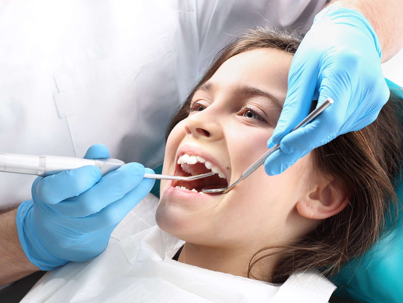 Young Girl Receiving Orthodontic Dental Examination From Dentist Wearing Blue Gloves.